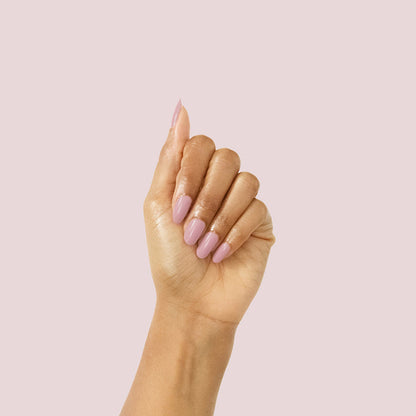Hand with glossy mauve manicure showcasing World Lit polish against a soft pale pink background